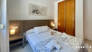 Una camera d'albergo con un letto, comodini, un armadio in legno e un'opera d'arte appesa al muro.