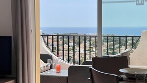 Un balcone con tavolo, sedie e vista sul mare e sugli edifici.