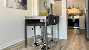 A modern kitchen with stainless steel appliances, a bar area with stools, and a dining table.