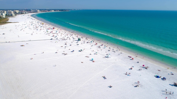 An aerial view of a beach with numerous umbrellas and people.