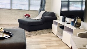 A modern living room with a grey sectional sofa, a white entertainment unit, and a flat-screen TV.