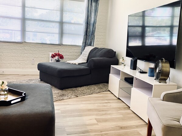 A modern living room with a grey sectional sofa, a white entertainment unit, and a flat-screen TV. - Charming Downtown Sarasota home (Sarasota)