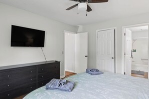 A bedroom with a bed, a dresser, a television, and a ceiling fan. - Spacious 2BR Ideal for Long-Term Business Stays (Calhoun)