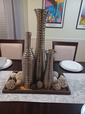 A dining table with a centerpiece of stacked metallic vases and decorative spheres.