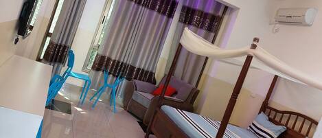 Une chambre à coucher avec un lit à baldaquin, un ventilateur de plafond et une fenêtre éclairée de lumière violette.