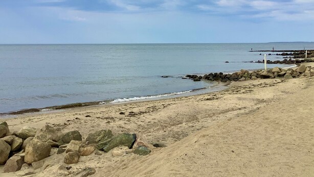 A beach with a rocky shoreline, calm sea, and a clear sky. - Steps to a private beach in a classic Cape cottage. Pet-friendly! (Dennis)