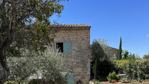 A stone building with a small window and a door, surrounded by a garden with various plants and a swimming pool. - Maison DE Hameau - 4 KM Roussillon - 8 KM Gordes (Saint-Saturnin-lès-Apt)
