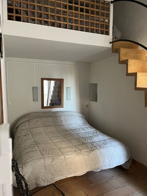 A bedroom with a large bed, a wooden staircase, and a small window. - Maison DE Hameau - 4 KM Roussillon - 8 KM Gordes (Saint-Saturnin-lès-Apt)