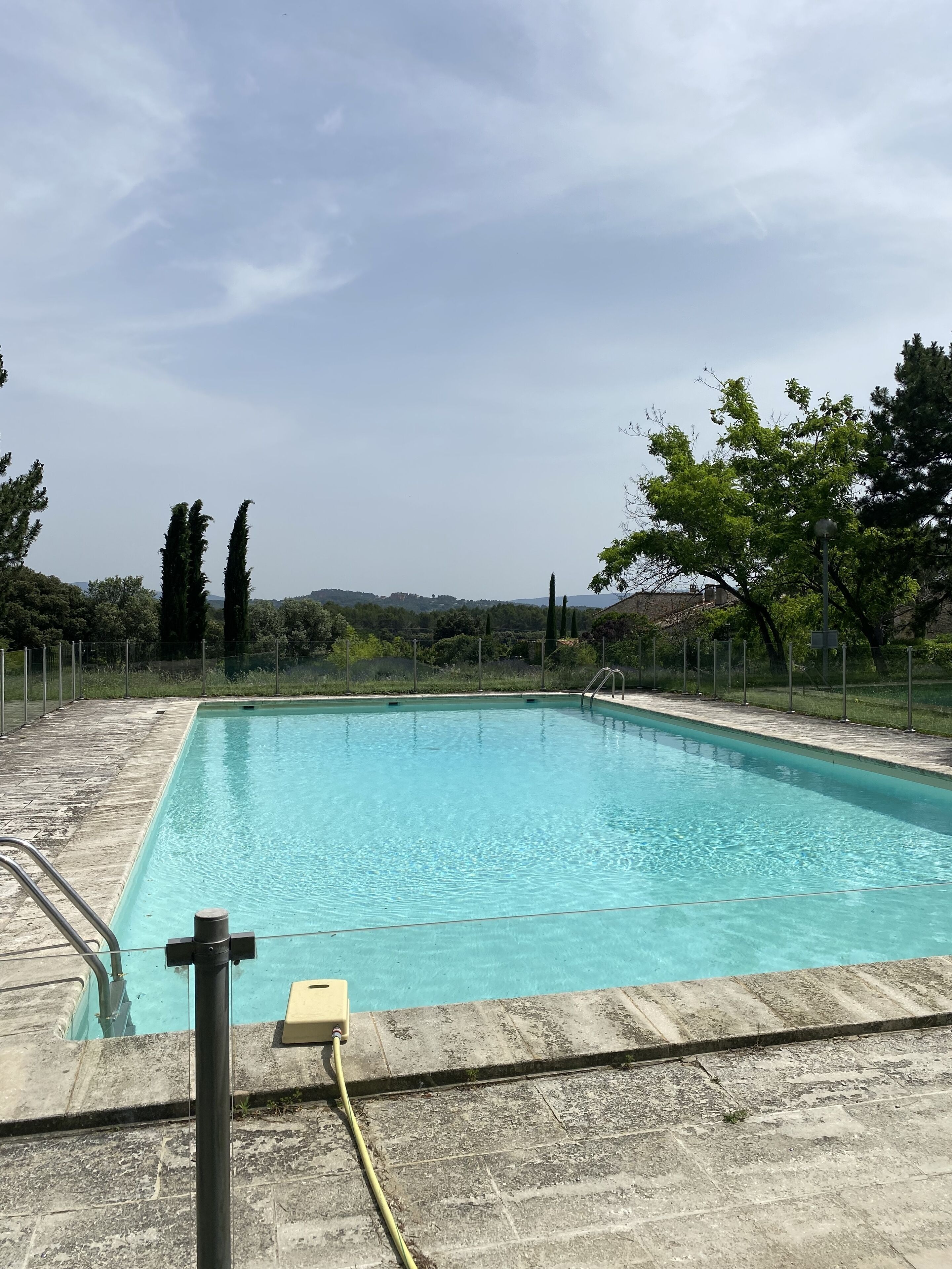 A rectangular swimming pool with clear blue water, surrounded by a stone deck.