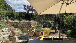 An outdoor patio with a table and chairs, surrounded by potted plants and a stone wall. - Maison DE Hameau - 4 KM Roussillon - 8 KM Gordes (Saint-Saturnin-lès-Apt)