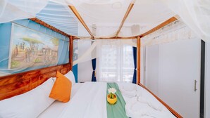 A room with a bed, a painting, a window, and a door. - Zanzibar, Fumbatown B08-03- 20 (Fumba)