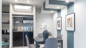 Une cuisine moderne dotée d’appareils électroménagers intégrés, un coin repas avec une table et des chaises, et des œuvres d’art encadrées accrochées au mur.