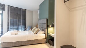 Une chambre moderne avec un grand lit, une table de chevet et une fenêtre équipée de stores.