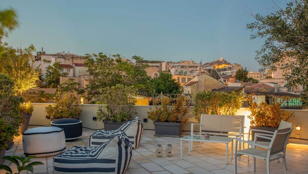 Une terrasse sur le toit, aménagée avec des sièges, des plantes en pot et offrant une vue sur le paysage urbain.