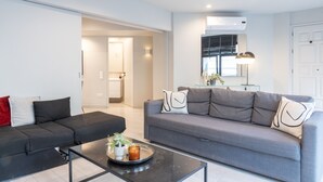 Un salon moderne avec un canapé gris, un canapé noir et une table basse agrémentée d’objets décoratifs.
