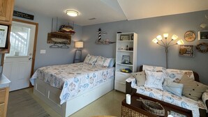 Ein Schlafzimmer mit einem Bett, einem Nachttisch, einer Kommode und einer Wandlampe.