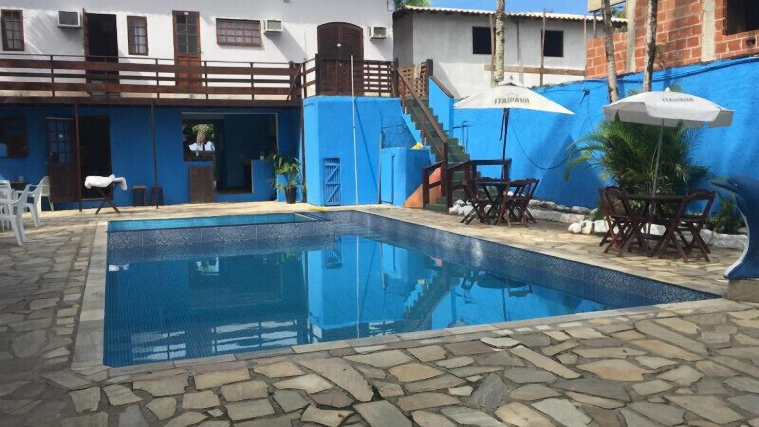 A swimming pool with stone tiles, a wooden deck, and outdoor furniture.