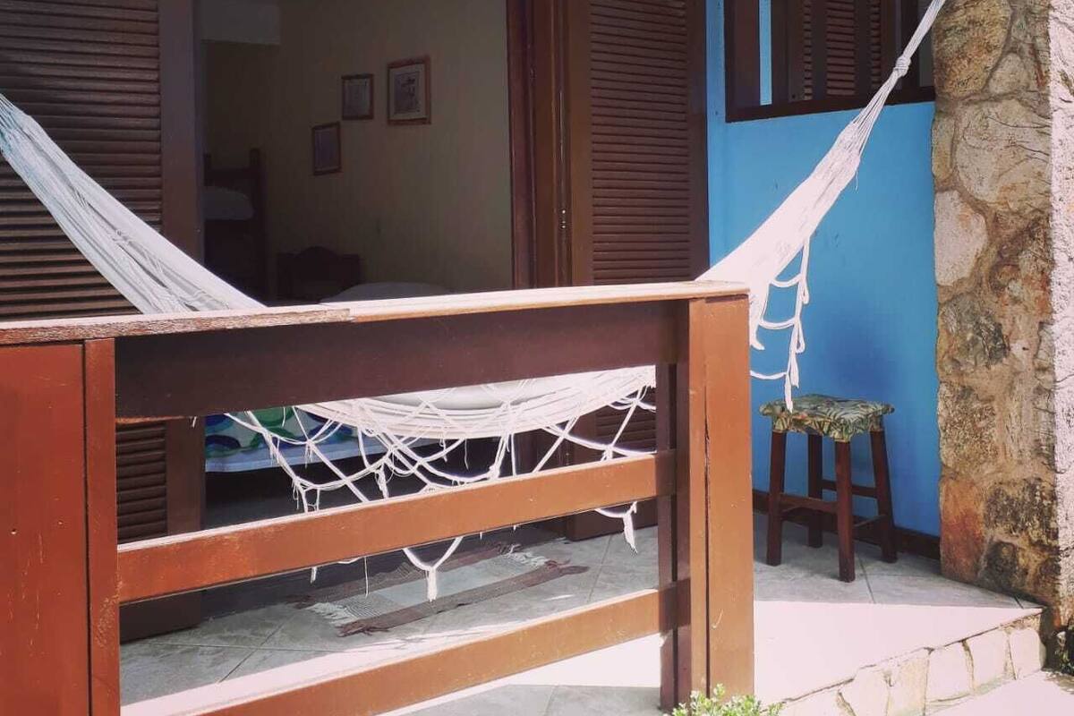 A room with a hammock, wooden furniture, and a stone pillar.