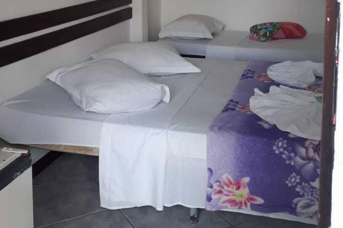 A room with two beds, a hanging light fixture, and a painting on the wall.