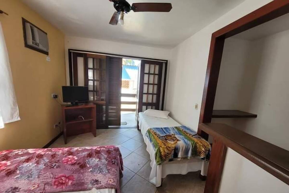 A room with two beds, a TV, a ceiling fan, and a door leading outside.
