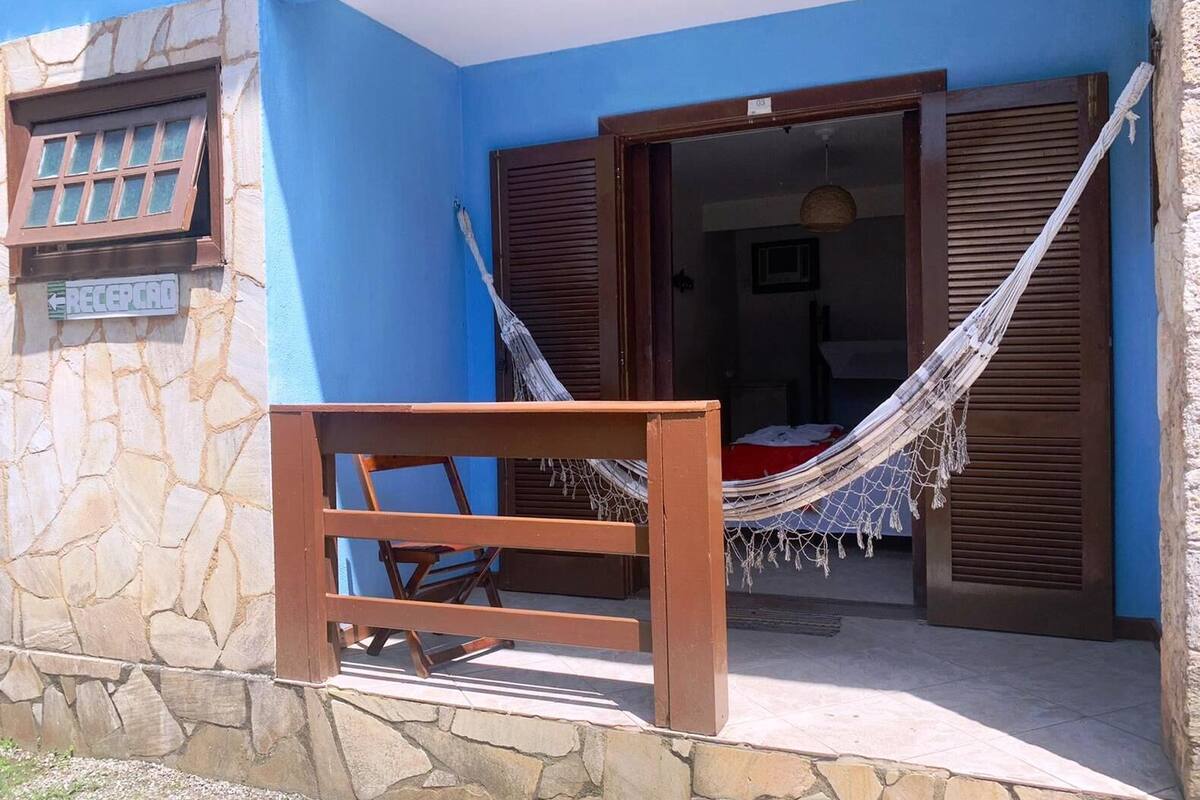 A blue building with a stone facade, a hammock, and a wooden bench outside.