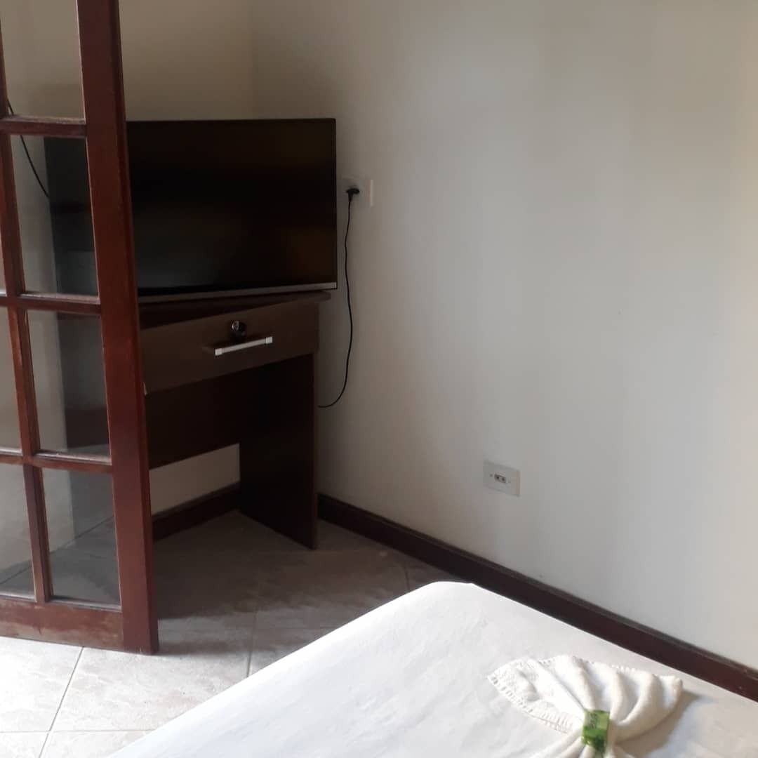 A hotel room with a bed, a television on a desk, and a sliding door.