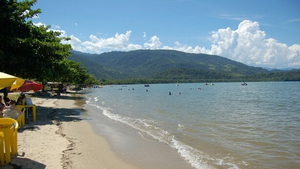 A beach with clear water, people swimming, and boats. - Pousada Bella Spiaggia (Paraty)