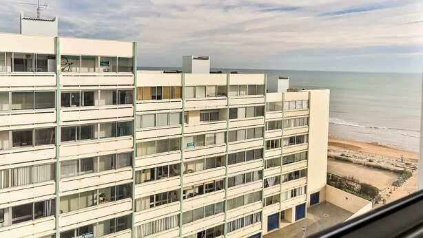 Ein mehrstöckiges Hotel mit Balkonen mit Blick auf einen Strand.