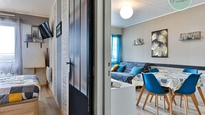 Ein modernes Zimmer mit einem Bett, einem Schreibtisch und einer Essecke mit Stühlen und einem Tisch.