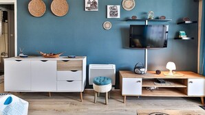 Ein modernes Wohnzimmer mit einer türkisfarbenen Akzentwand, einem Flachbildfernseher, einer weißen Unterhaltungsanlage und einem Holztisch.