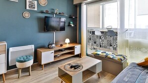 Ein modernes Wohnzimmer mit Fernseher, Sitzgelegenheiten und Wanddekoration.