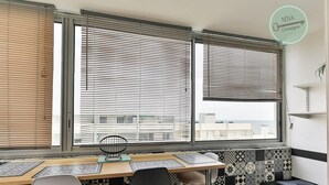 Eine Küche mit Essbereich, mit einem Fenster ausgestattet mit Jalousien, einem Tisch mit Stühlen und Wandfliesen mit Muster.