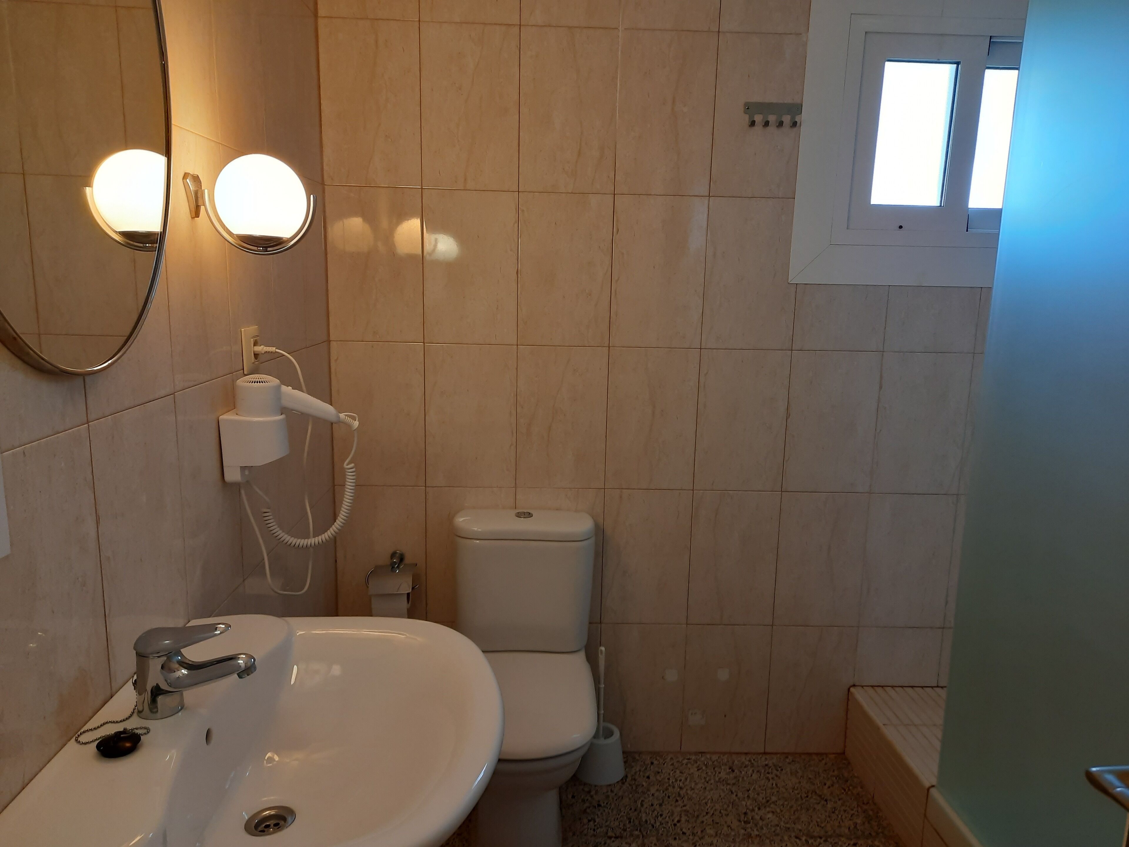 A bathroom with a sink, toilet, and a mirror with lights.