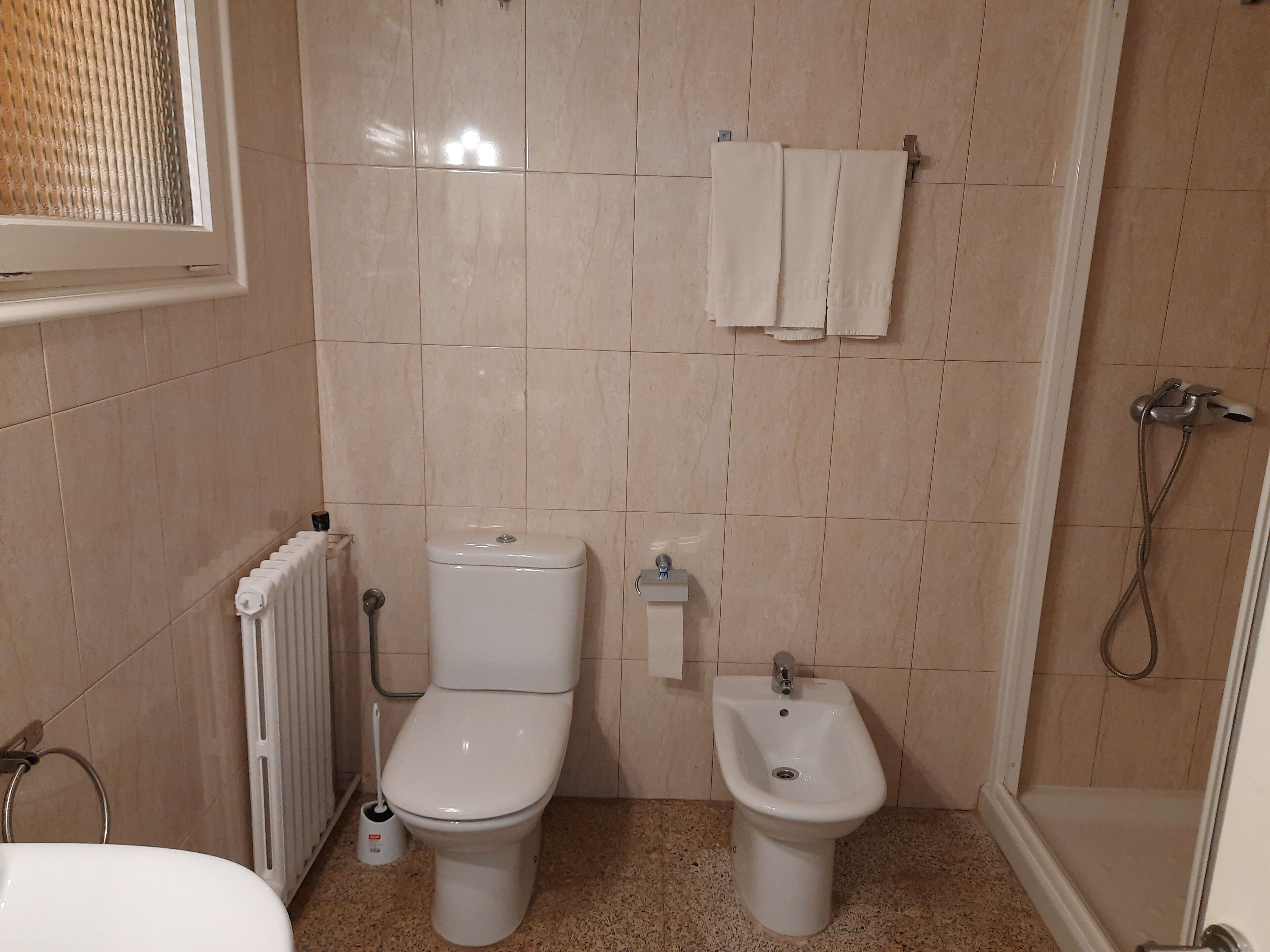 Un baño con inodoro, bidé y radiador.