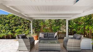 An outdoor patio with wicker furniture, a white ceiling, and lush greenery. - 3316 Villa San Donato by Perle di Puglia (Taranto)