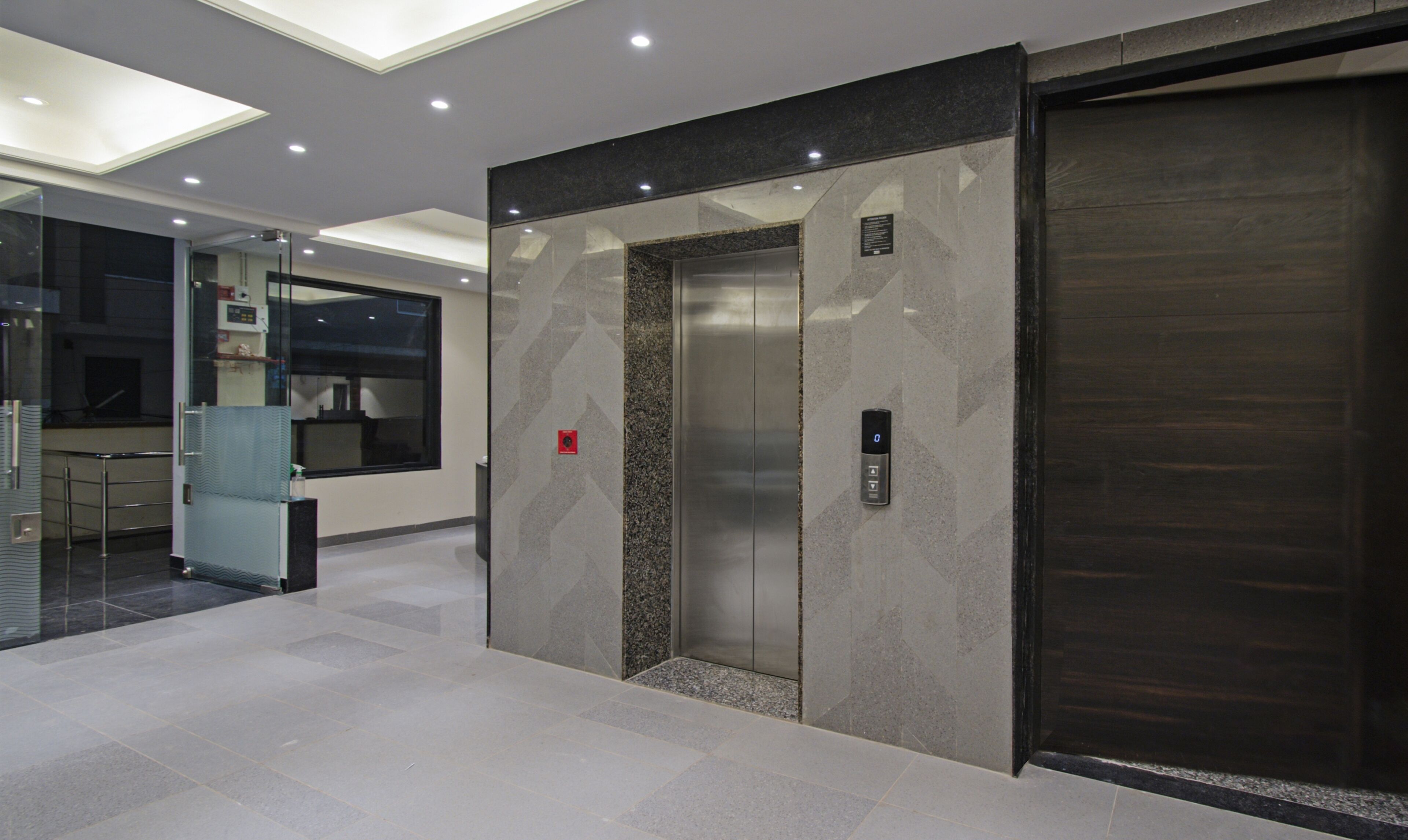 An elevator in a modern building with a glass door and a control panel.
