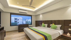 A modern hotel room with a large bed, a desk, and a window with a city view. - Treebo Pink City Grand (Jaipur)