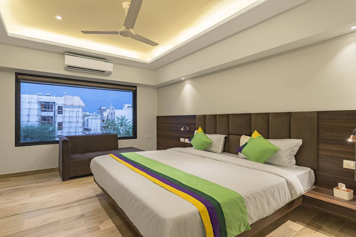 Une chambre d’hôtel moderne dotée d’un grand lit, d’un bureau et d’une fenêtre donnant sur la ville.