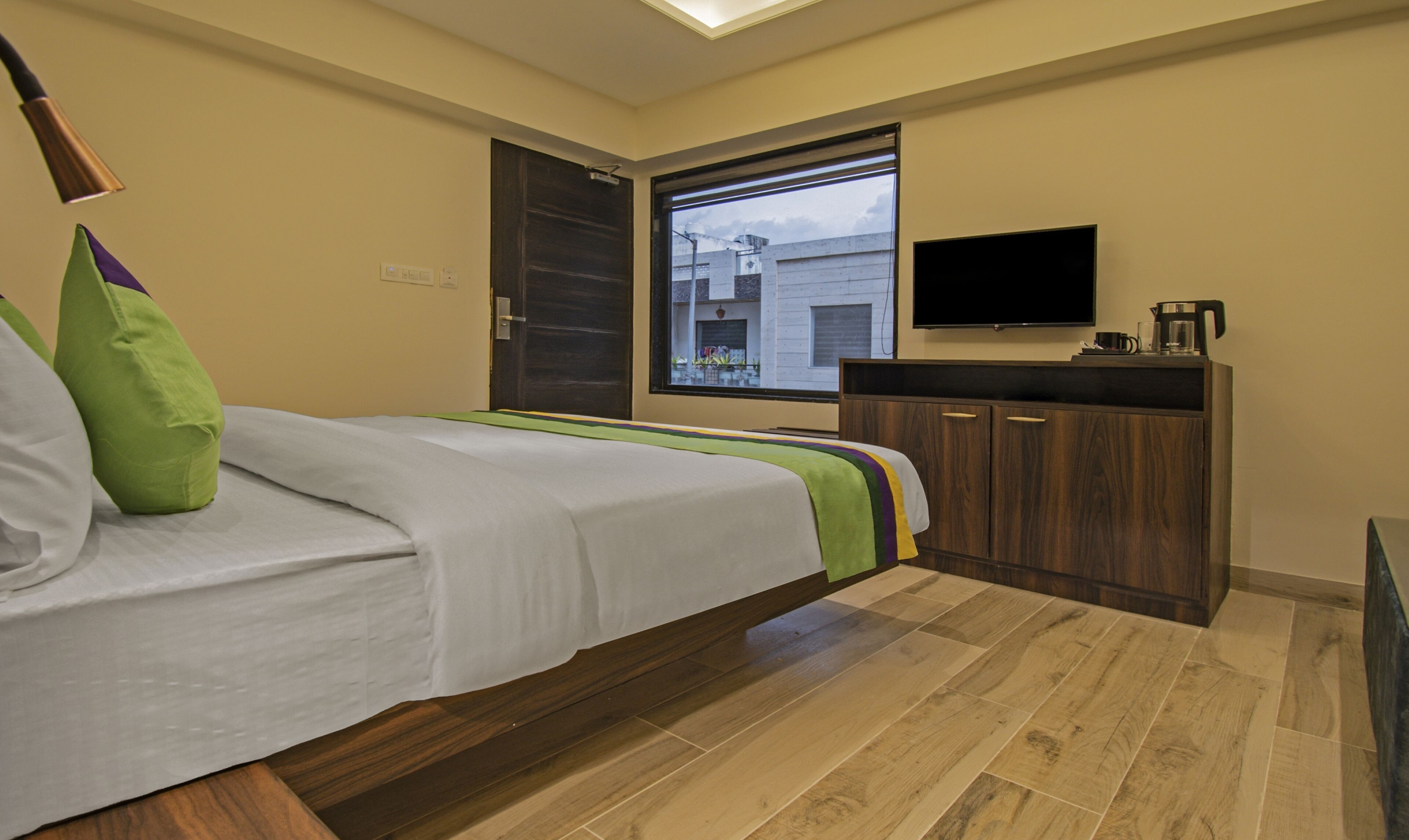 A bedroom with a bed, a TV, a window, and a wooden cabinet.