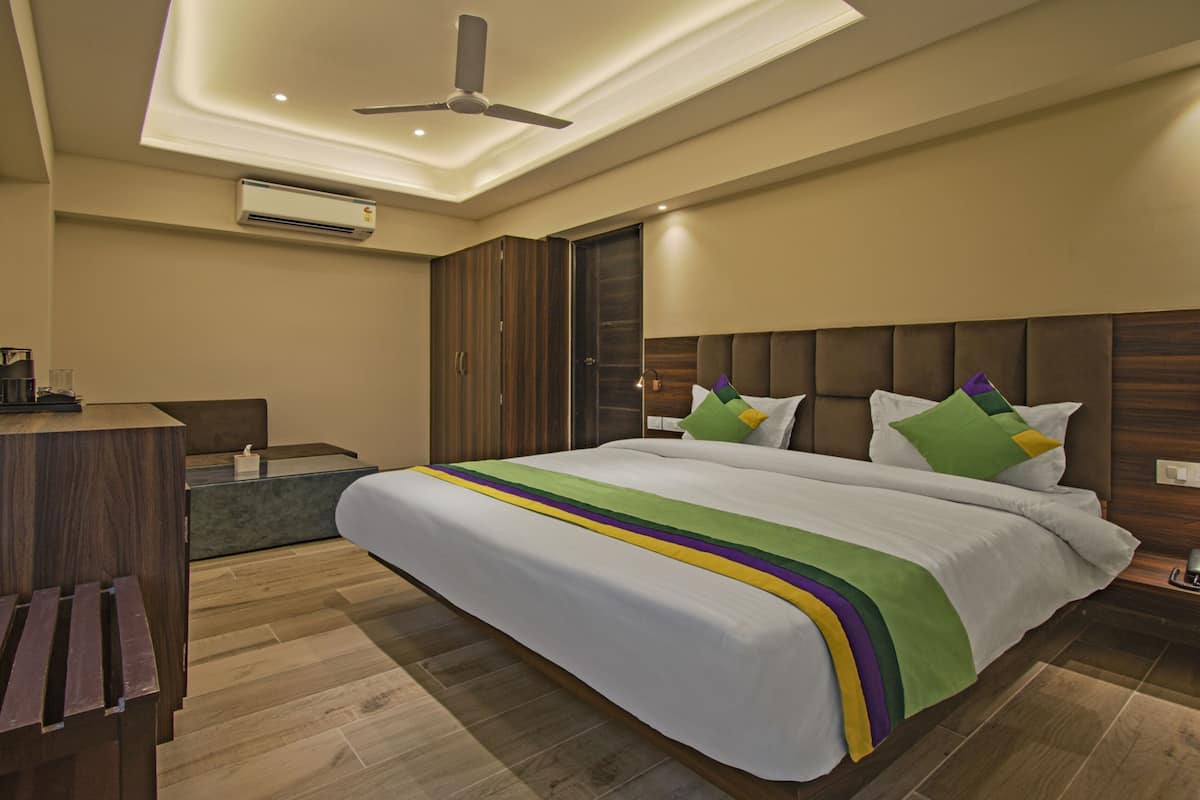 Une chambre d’hôtel moderne, dotée d’un grand lit, d’un bureau avec un téléphone et d’un ventilateur de plafond.