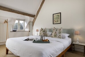 A bedroom with a large bed, a bedside table, a lamp, and a window. - Beautifully presented dog friendly - Bea's Cottage (Ampney Crucis, near Cirencester)