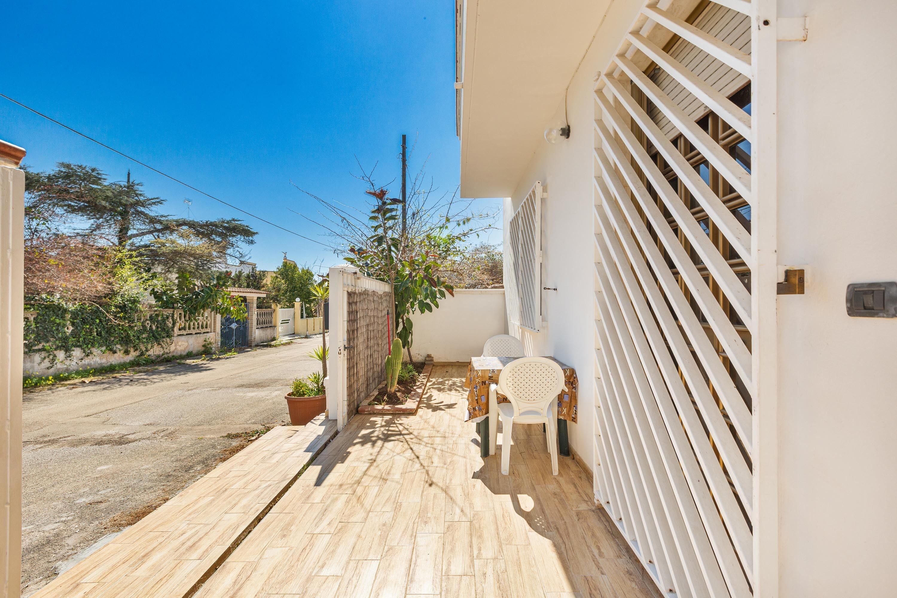 Un étroit sentier pavé mène à un bâtiment blanc doté d’un espace extérieur abrité avec des sièges.