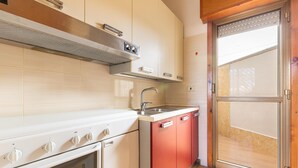 A kitchen with a stove, oven, sink, and red cabinets. - 3304 Terra del Salento - Mono Costa by Barbarhouse (Porto Cesareo)