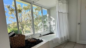 Una stanza con un'ampia finestra, una vasca da bagno e un pavimento piastrellato.