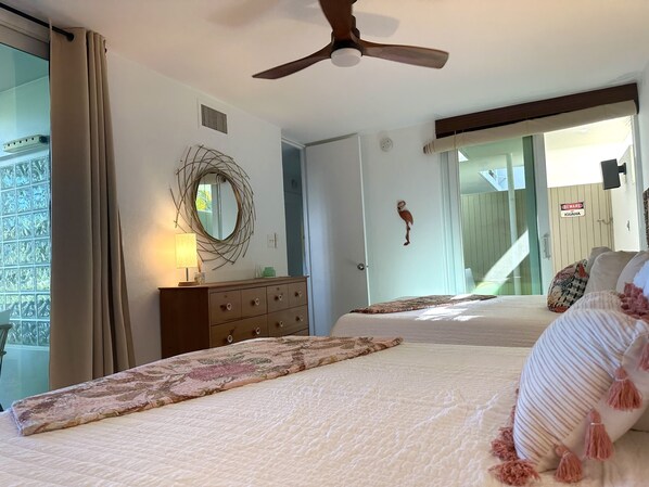 A bedroom with two beds, a ceiling fan, a dresser, a mirror, and a view of the outside. - Unplug & Unwind, Unplug & Unwind St. Thomas Style (Northside)
