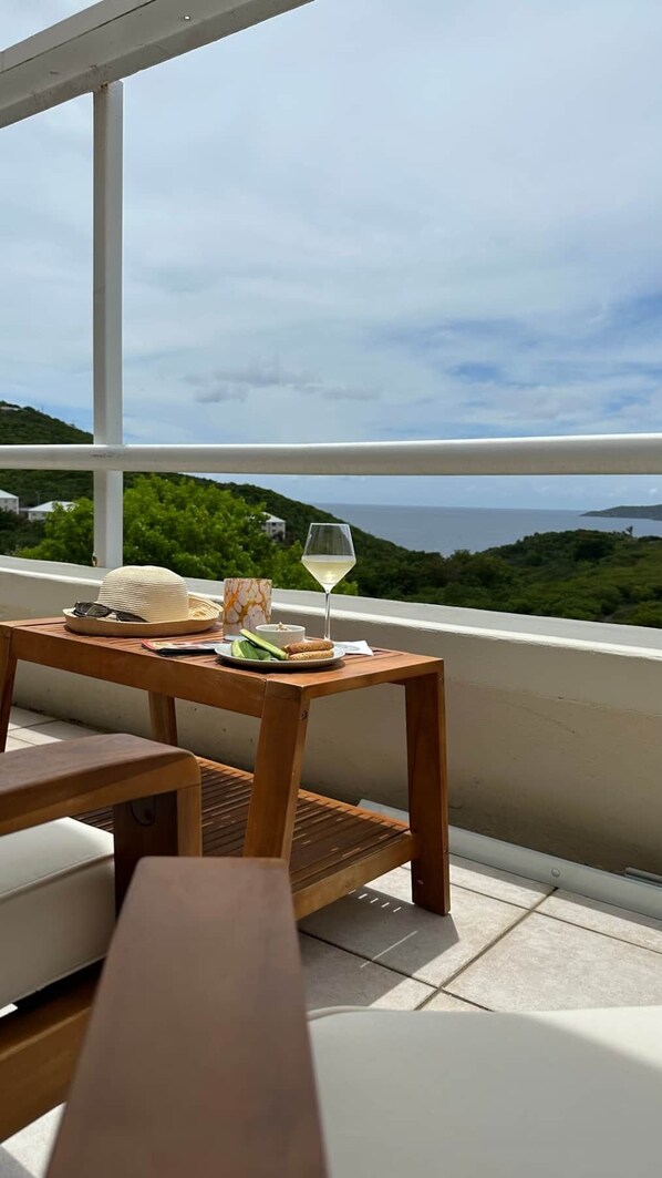A balcony with a wooden table, a white chair, and a glass of white wine. - Unplug & Unwind, Unplug & Unwind St. Thomas Style (Northside)