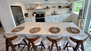 Una cucina moderna con una grande isola, mobili bianchi e vista su una zona verde.