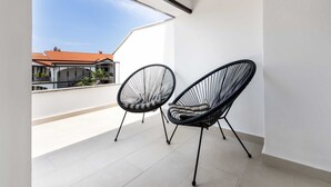 A balcony with two black wire-framed chairs and a white tiled floor.