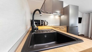 A modern kitchen with a black sink, stainless steel appliances, and wooden countertops.