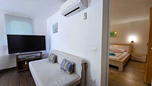 Ein modernes Wohnzimmer mit Sofa, Fernseher und Klimaanlage.